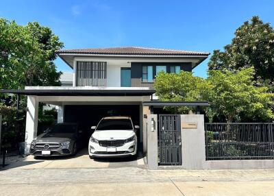 Exterior view of a modern two-story house with a driveway and two parked cars