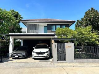 Exterior view of a modern two-story house with a driveway and two parked cars