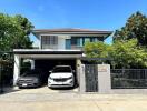 Exterior view of a modern two-story house with a driveway and two parked cars