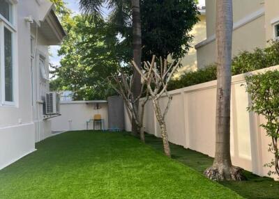 Well-maintained backyard with artificial grass and trees