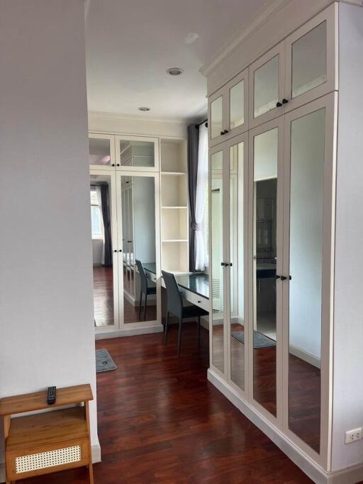 Spacious bedroom with mirrored wardrobe and wooden flooring