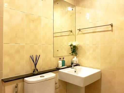 Modern beige-tiled bathroom with sink, toilet, and vanity mirror