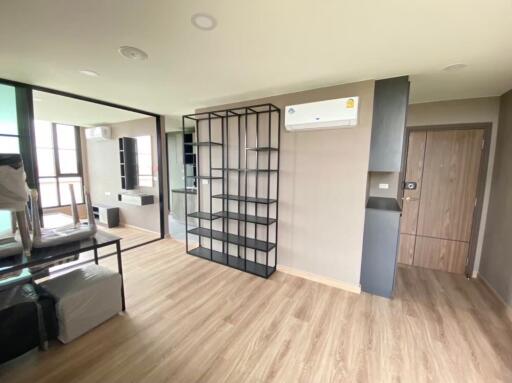 Spacious bedroom with wooden flooring, large mirror, and shelving unit