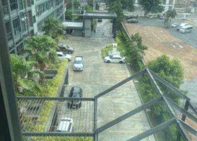 View from the balcony overlooking the parking area, pool, and nearby buildings