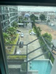 View from the balcony overlooking the parking area, pool, and nearby buildings