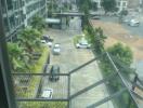 View from the balcony overlooking the parking area, pool, and nearby buildings