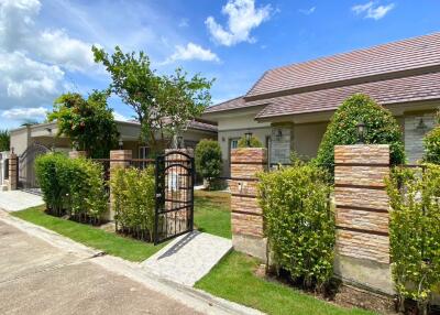 Exterior view of a residential property with a well-maintained garden and gate