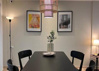 Modern dining room with black table and chairs, decorative lamp, and wall art