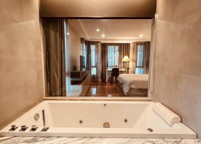 Luxurious bathroom with a marble jacuzzi tub and view into a modern bedroom