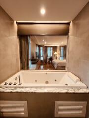 Luxurious bathroom with a marble jacuzzi tub and view into a modern bedroom