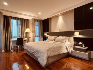 Cozy bedroom with a large bed, wooden flooring, and a desk