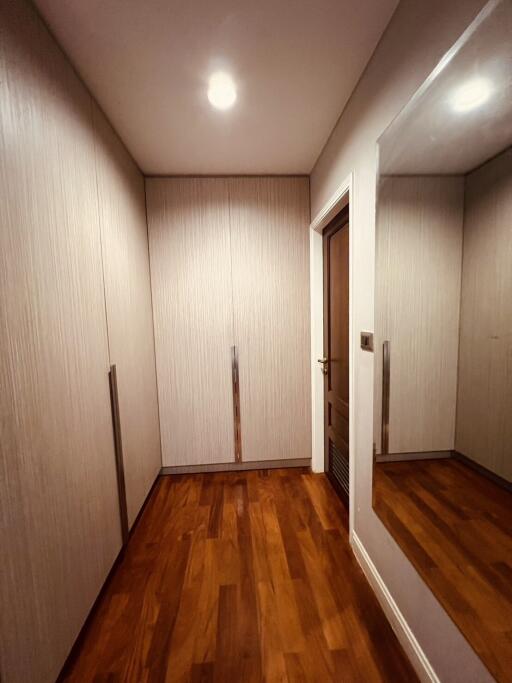 Spacious walk-in closet with wooden flooring and built-in cabinets