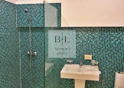 Modern bathroom with green mosaic tiles and glass shower