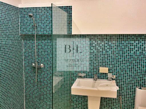 Modern bathroom with green mosaic tiles and glass shower