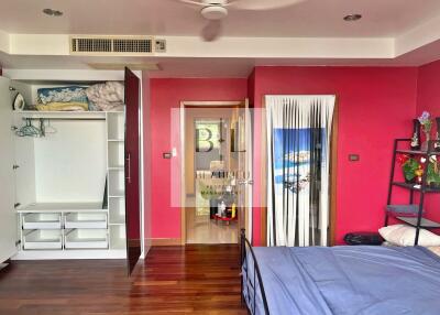 Spacious bedroom with red accent wall and organized closet