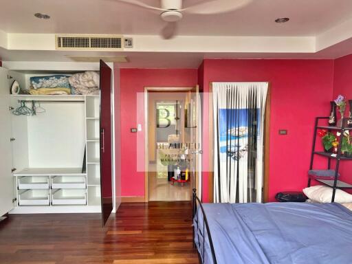 Spacious bedroom with red accent wall and organized closet