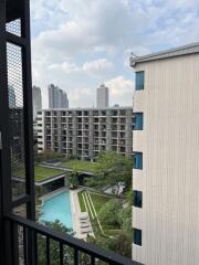 View from the balcony overlooking a pool and modern buildings