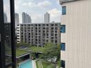 View from the balcony overlooking a pool and modern buildings