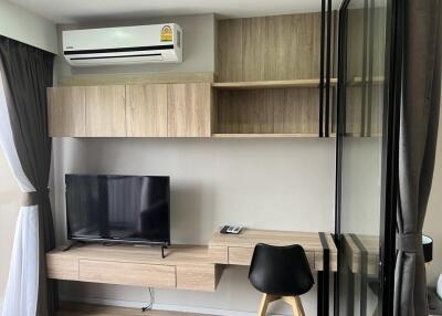 Modern living room with built-in wooden cabinetry, air conditioning, flat-screen TV, and glass partition