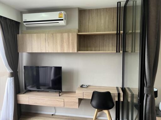 Modern living room with built-in wooden cabinetry, air conditioning, flat-screen TV, and glass partition