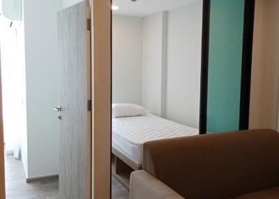 Bedroom seen through a glass partition with a sofa in the foreground