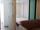 Bedroom seen through a glass partition with a sofa in the foreground