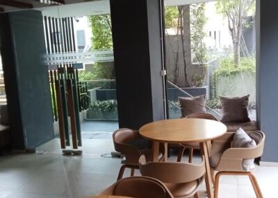 Modern seating area with wooden tables and chairs near large windows