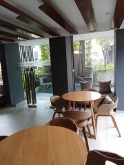 Modern seating area with wooden tables and chairs near large windows