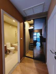 Hallway connecting bathroom and living space with wooden flooring and a mirrored sliding door