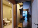 Hallway connecting bathroom and living space with wooden flooring and a mirrored sliding door