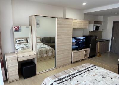 Modern studio apartment with bed, wardrobe, vanity, TV, and kitchenette