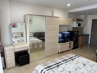 Modern studio apartment with bed, wardrobe, vanity, TV, and kitchenette