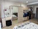 Modern studio apartment with bed, wardrobe, vanity, TV, and kitchenette