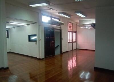 Spacious empty office space with wooden floors and fluorescent lighting