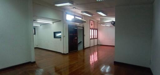 Spacious empty office space with wooden floors and fluorescent lighting