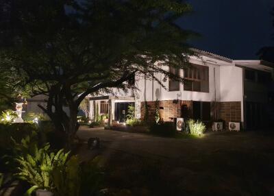 Well-lit building exterior at night with surrounding greenery