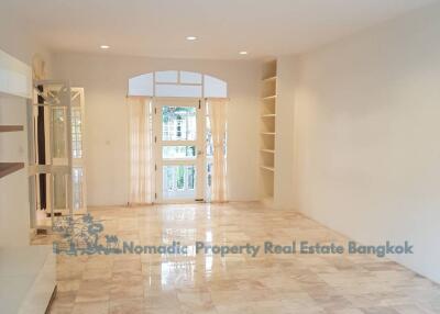 Spacious living room with marble floor, built-in shelves, and large windows