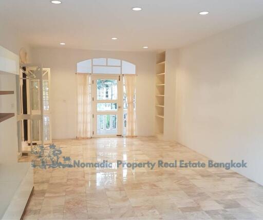 Spacious living room with marble floor, built-in shelves, and large windows