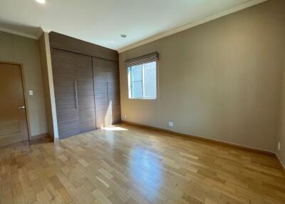 Spacious empty bedroom with wooden floor and large window