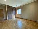 Spacious empty bedroom with wooden floor and large window