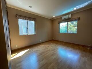 Empty bedroom with wooden floor and large windows