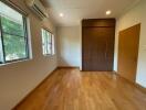 Empty bedroom with wooden flooring and large windows