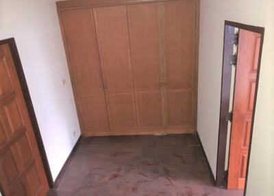 A bedroom with wooden closet and dark flooring