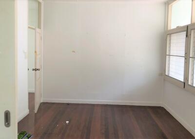 Empty bedroom with wooden floor and large windows