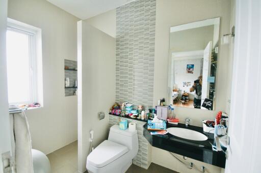 Modern bathroom with a large mirror, compact sink, and toilet.