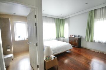 Spacious bedroom with attached bathroom, wooden flooring, and natural light