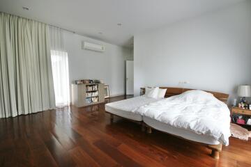 Spacious bedroom with large bed and wooden flooring.