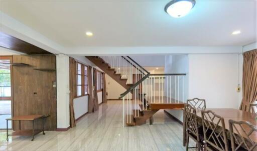 Main living area with stairs, dining table, and windows