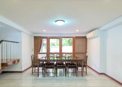 Dining room with a large dining table and chairs, near windows with curtains