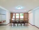 Dining room with a large dining table and chairs, near windows with curtains